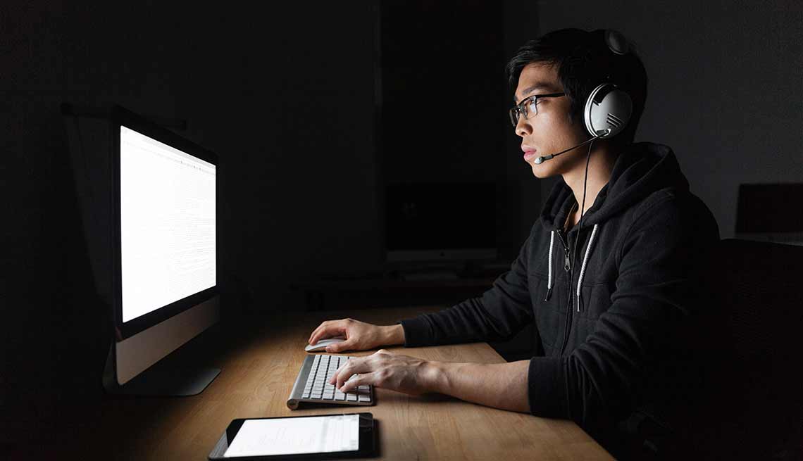 Hombre frente a una computadora con un sistema de audio y micrófono en su cabeza - Cuidado con las estafas de asistencia técnica