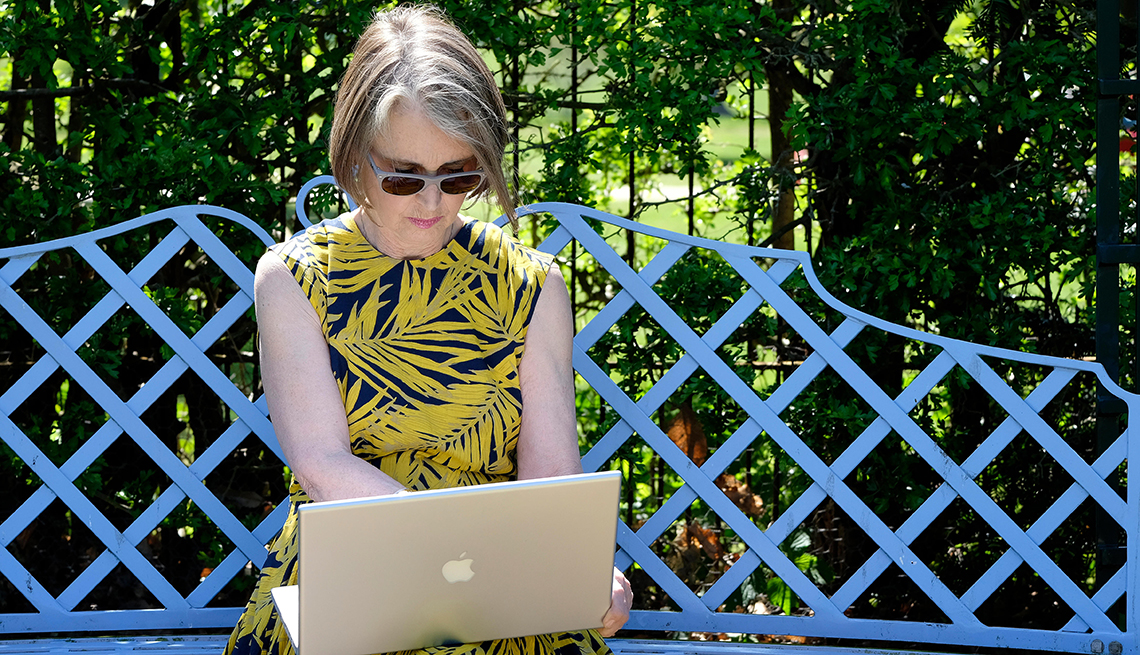 Woman wearing sunglasses using her computer outside