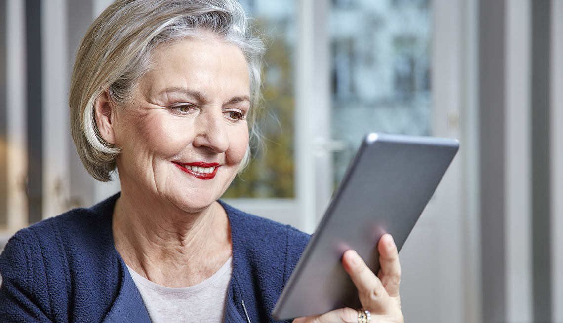 Mature woman smiling at her tablet