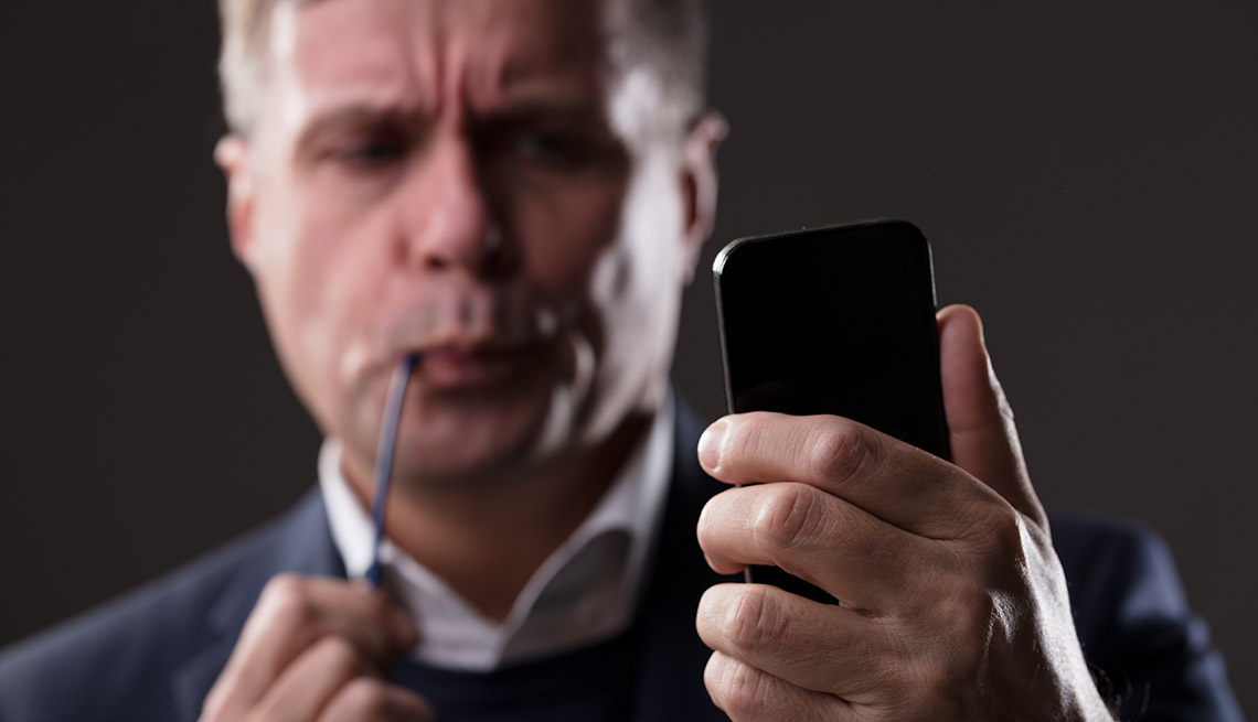 Hombre fumando una pipa y con un teléfono móvil en la mano.