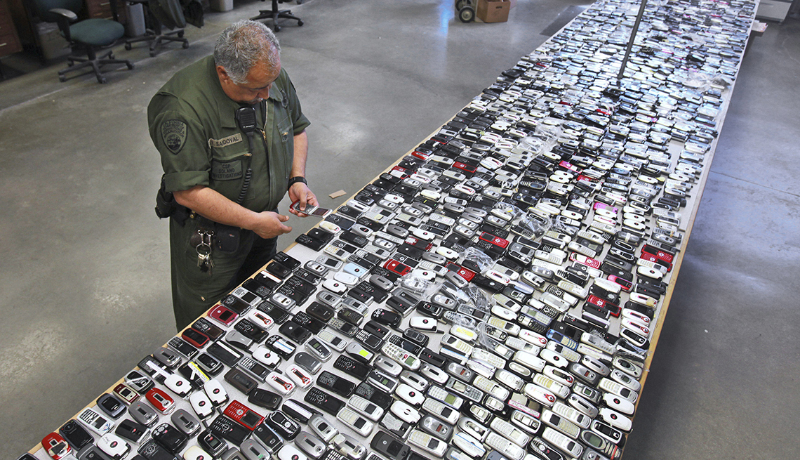 Guardia de una prisión frente a una mesa llena de teléfonos móviles ilegales.