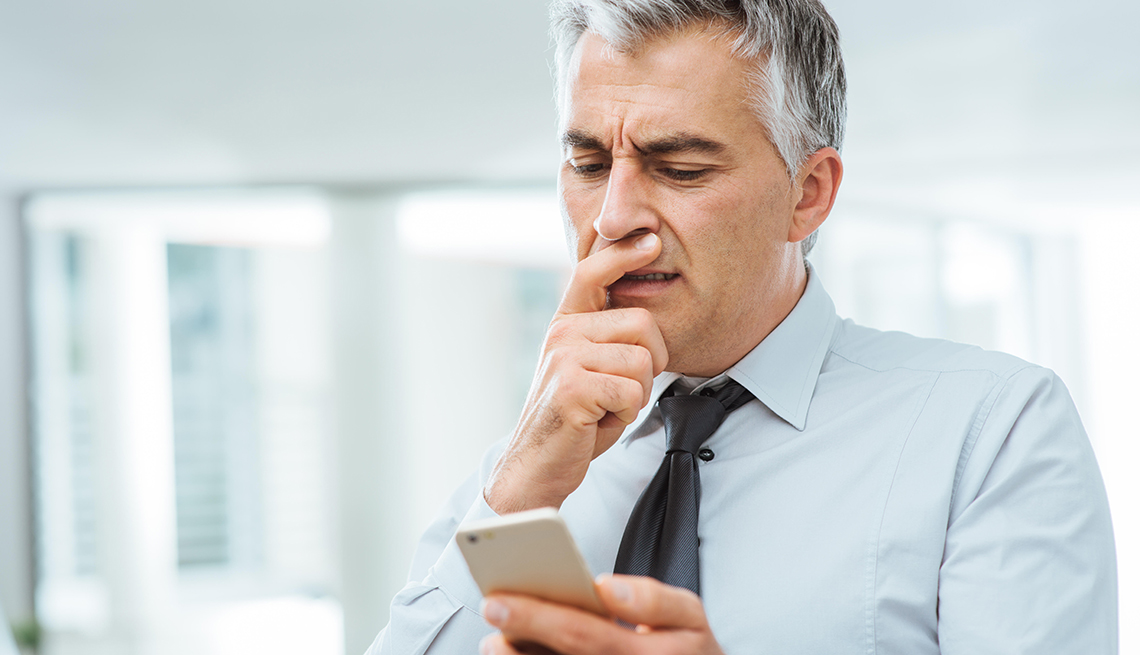 Businessman looks questioningly at smartphone