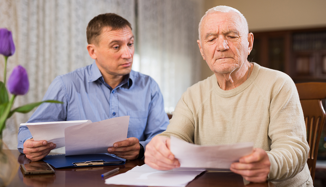 Hombre mayor al lado de otro mientras revisan unos documentos