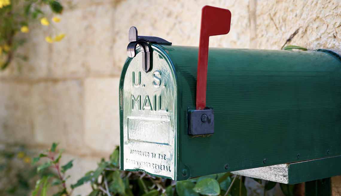 Buzón de correo verde frente a un muro