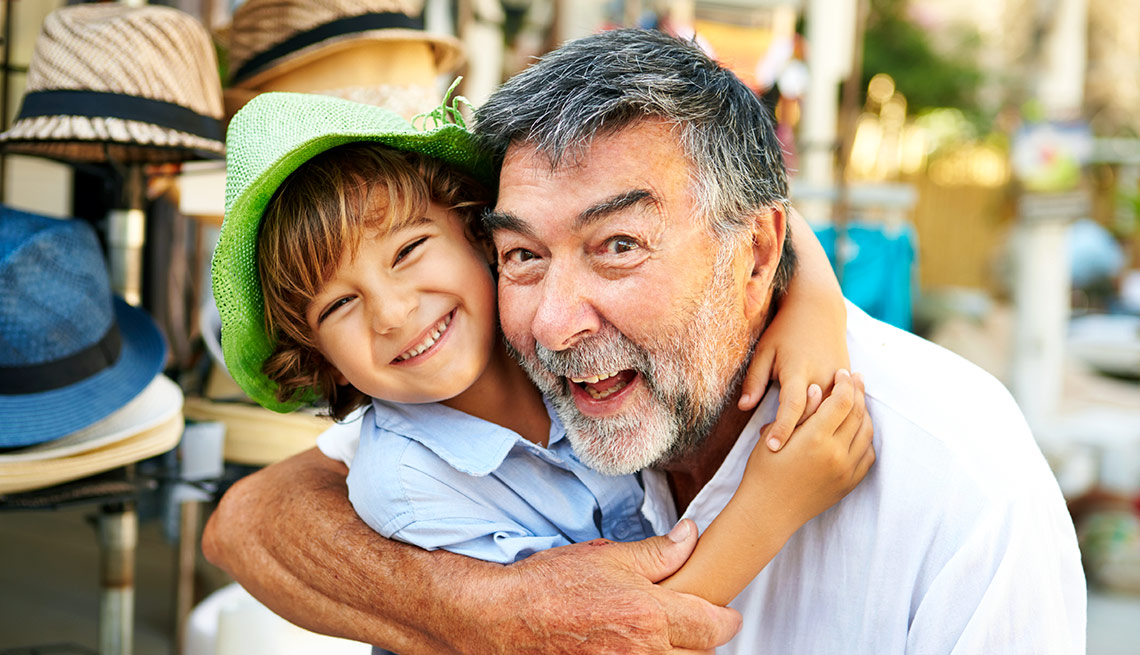 Nieto abrazando a su abuelo - Beneficios del gobierno para abuelos que cuidan nietos.