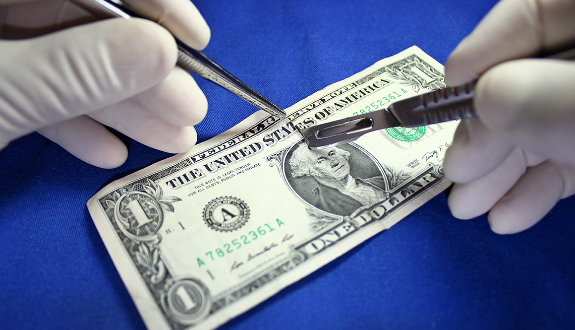 Surgical hands cutting a dollar bill 