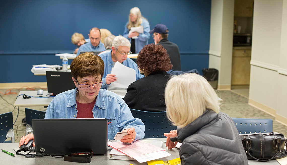 Volunteers from the AARP Foundation sit at computers with clients while preparing income tax returns for low- and moderate-income senior citizens