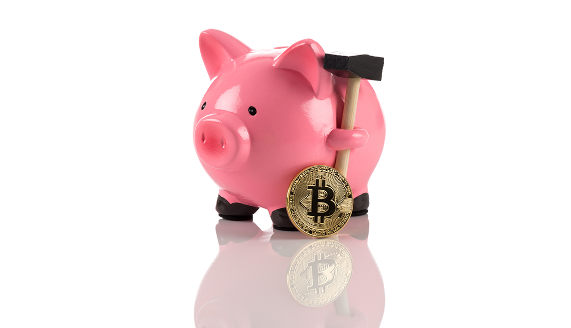 Moneda de bitcóin al lado de una alcancía rosada.