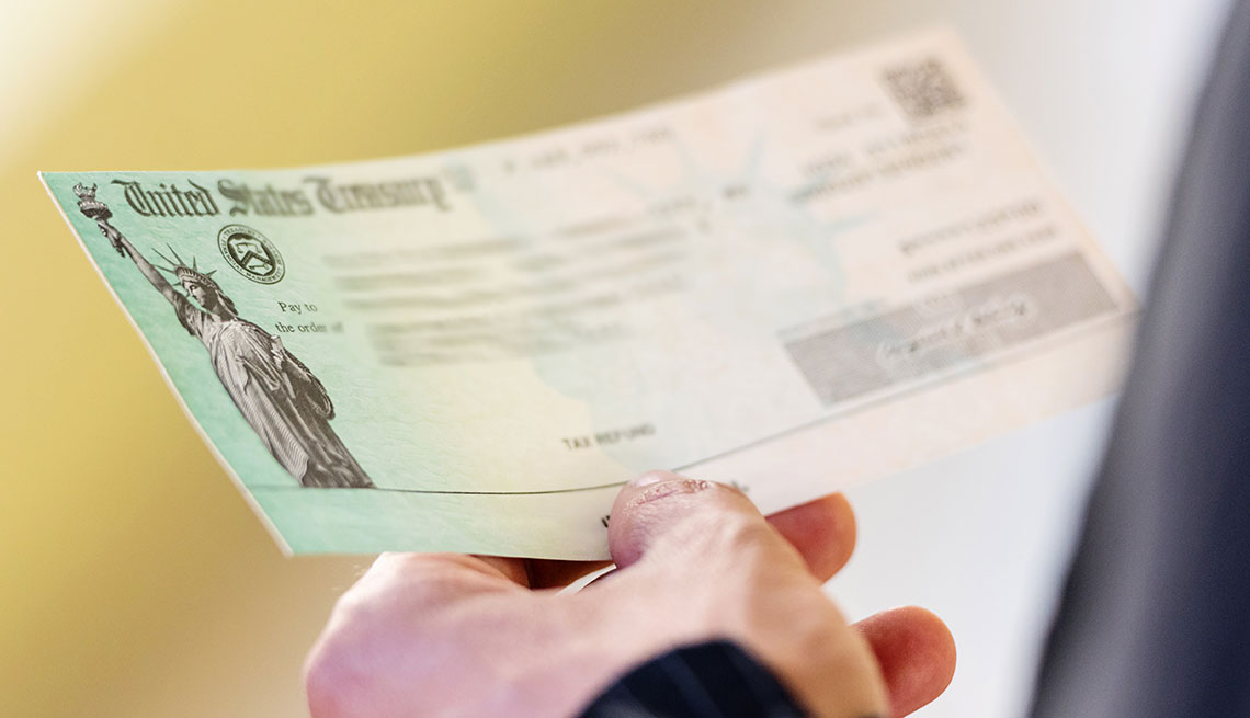 Mano de una persona sostiene un cheque del Departamento del Tesoro de Estados Unidos
