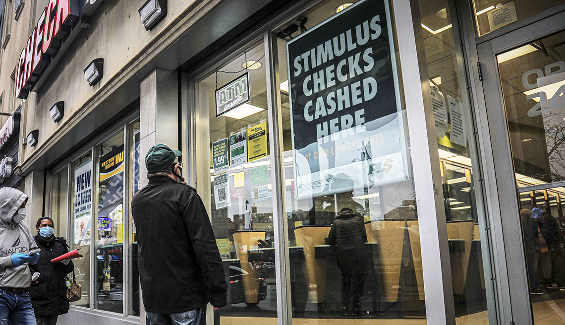 Personas con máscaras afuera de un centro de cambio de cheques de estímulo por efectivo en Brooklyn, Nueva York.