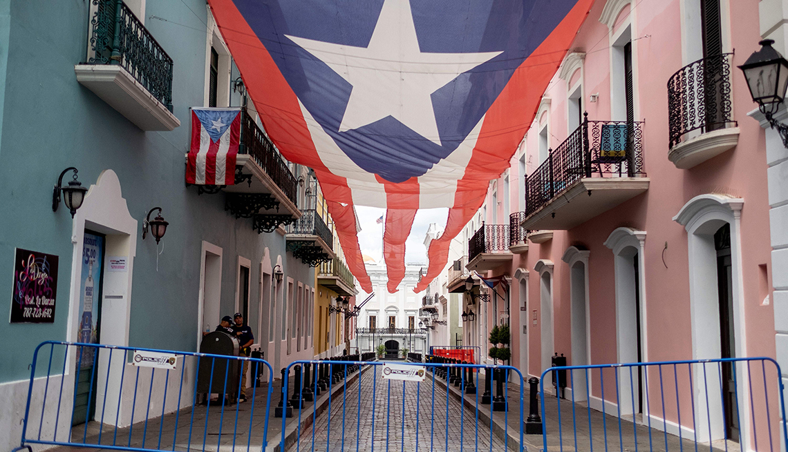 Vallas bloquean el acceso a una calle que en medio tiene la bandera de Puerto Rico sostenida de las casas en el Viejo San Juan, Puerto Rico.