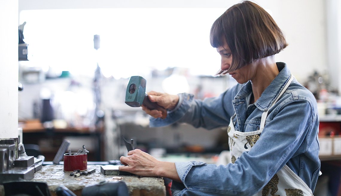 a jewelry designer working in her studio with a hammer