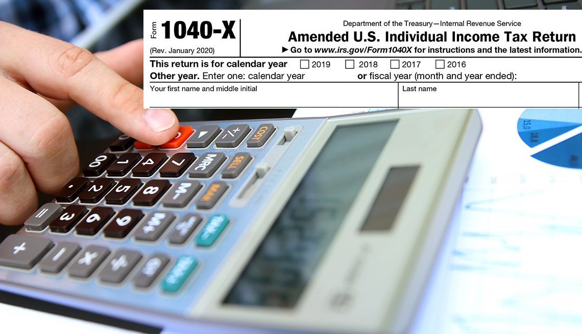 taxpayer with finger on calculator with part of the amended IRS tax form in view