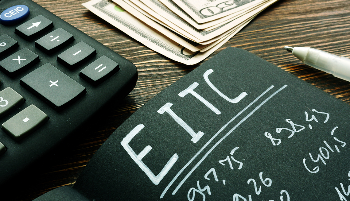 A handwritten page of EITC (Earned Income Tax Credit) numbers on a desk with money and a calculator 