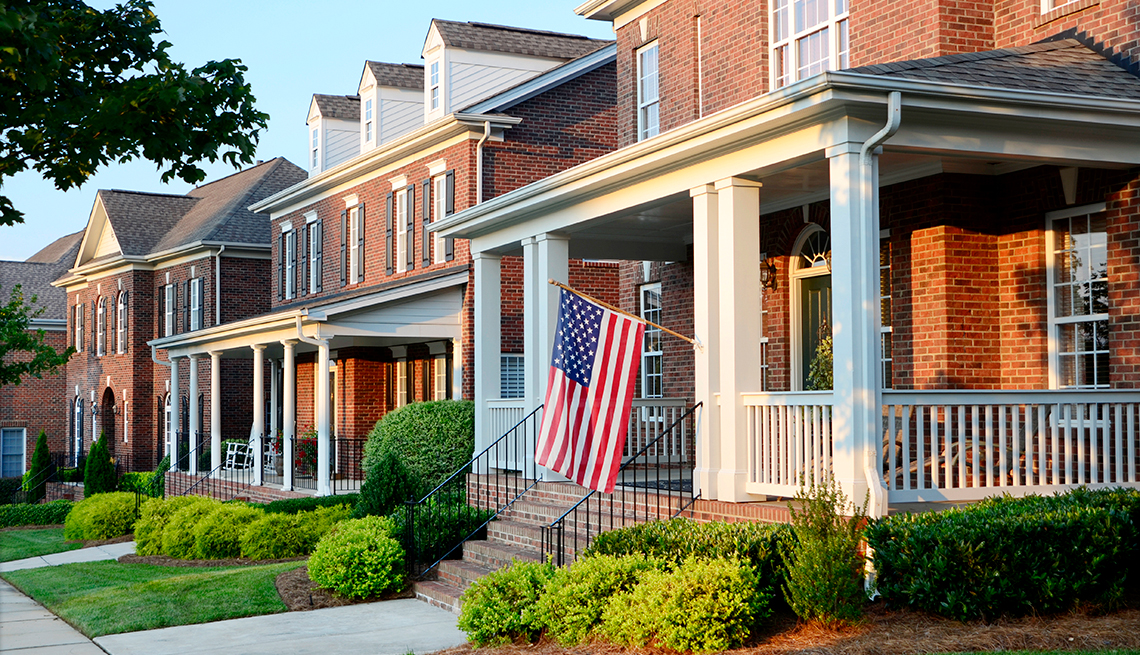 A row of traditional brick homes with an American Flag hanging from the front of the first house.