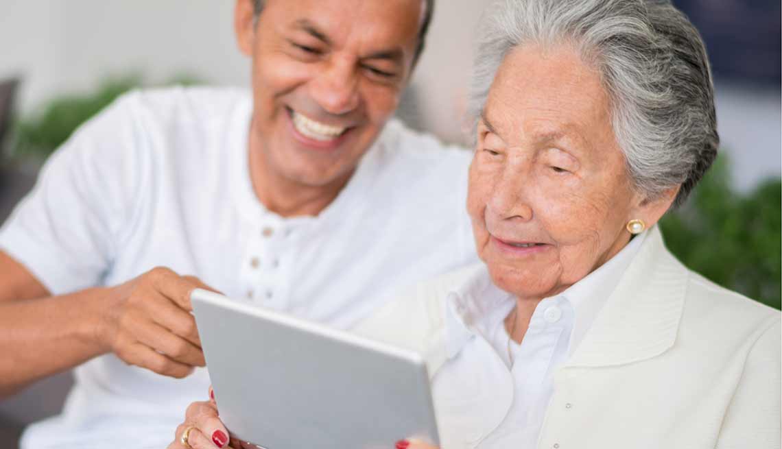 Hombre joven ayudando a una mujer mayor con la tecnología