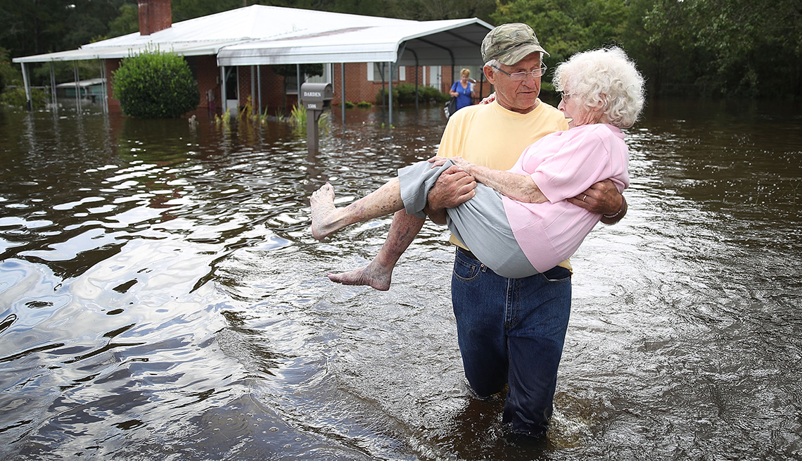 Man rescuing an older woman during Hurricane Florence.