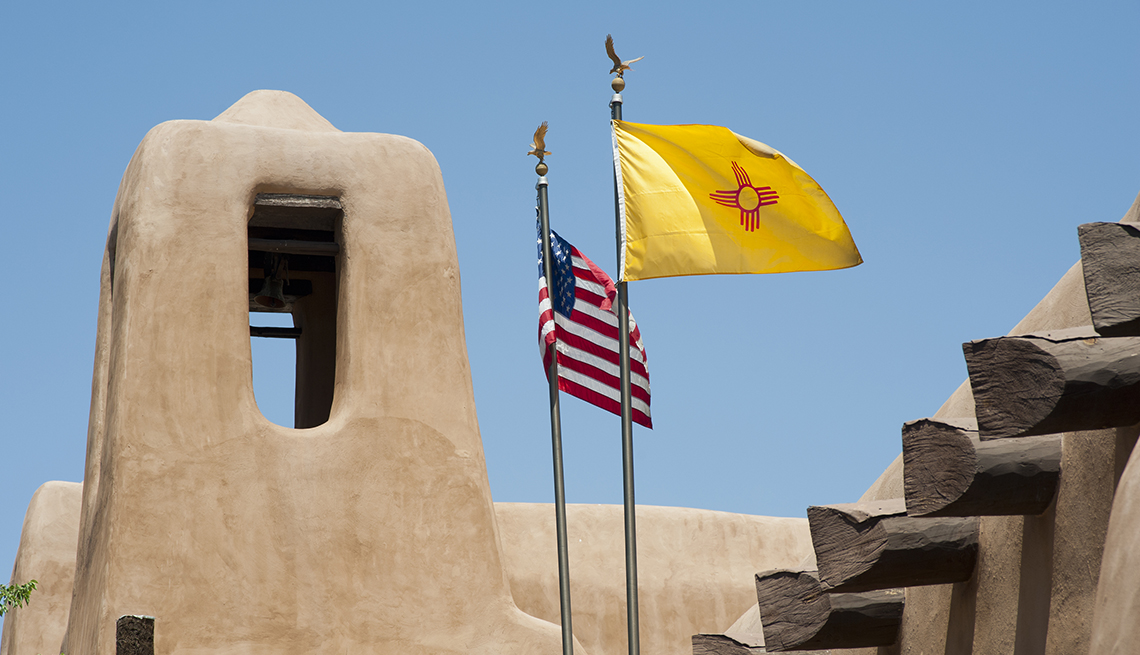 The flags of New Mexico and the United States fly over a building