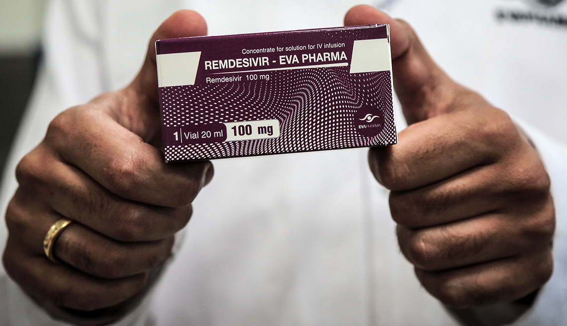 A person holding up a box of the drug Remdesivir