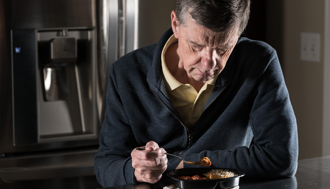 Hombre mayor luce deprimido mientras está comiendo solo en la cocina
