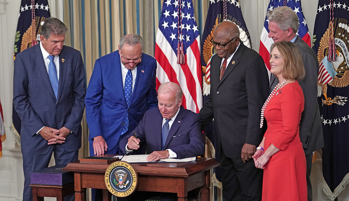 president joe biden signs the inflation reduction act surrounded by a few members of congress
