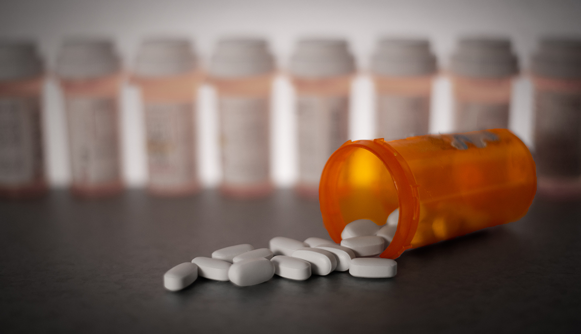Frasco de medicamentos con pastillas esparcidas sobre una mesa