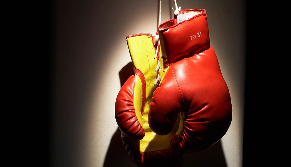 red boxing gloves hanging in a spotlight