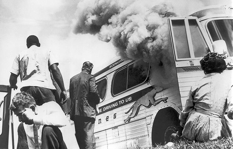 Freedom Riders on a Greyhound bus sponsored by the Congress Of Racial Equality (CORE), sit on the ground outside the bus after it was set afire by a group of whites in Anniston, Alabama, May 14, 1961, Historical Review of Leading Black Civil Rights Organizations