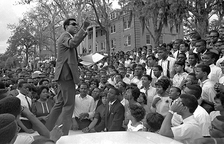 Stokely Carmichael, national head of the Student Nonviolent Coordinating Committee speaks from the hood of an automobile on the campus of Florida A&M University, April 16, 1967, in Tallahassee, Florida, Historical Review of Leading Black Civil Rights Organizations