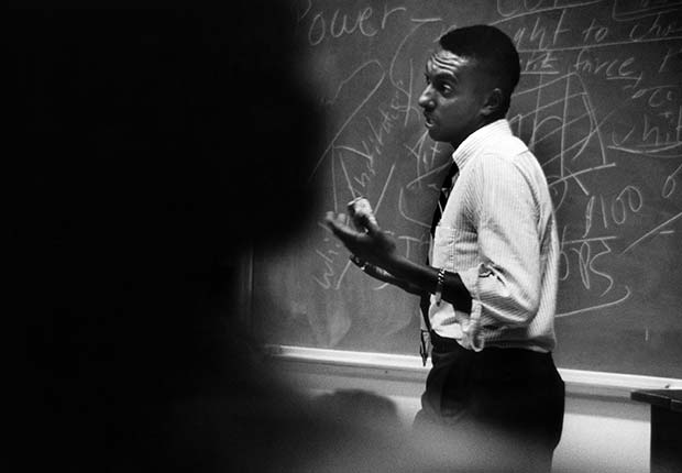 African American man speaking in front of a blackboard