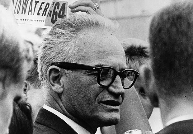 Barry Goldwater standing in a crowd with election signs behind him