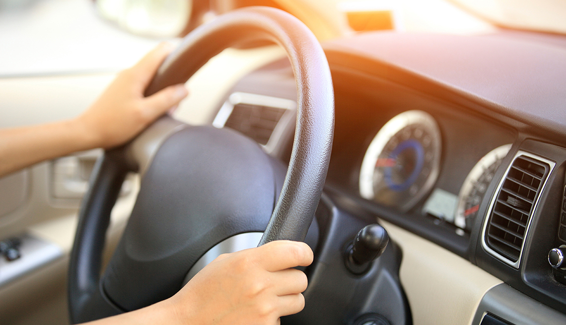 Las manos de una persona sujetan el volante de un automóvil.