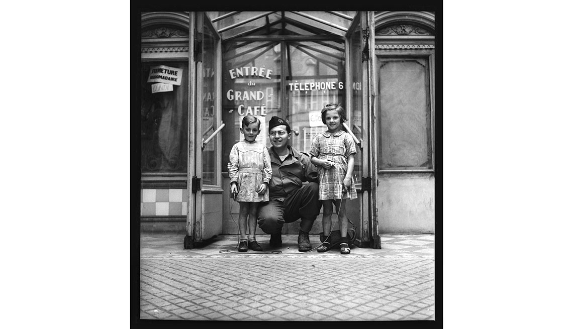 El fotógrafo John Morris se sitúa frente a la cámara y posa con dos niños franceses