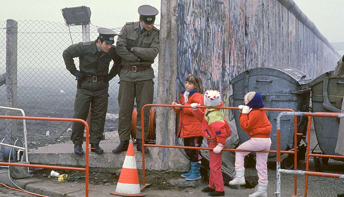 Militares conversan con unos niños a través del muro de Berlín