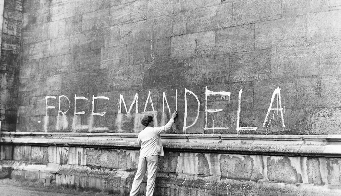 Hombre intenta borrar un escrito en una pared que dice Free Mandela