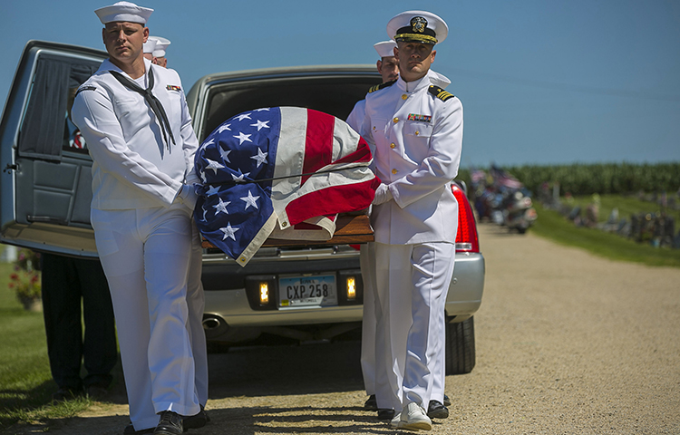 Sailors remove a casket from a hearse