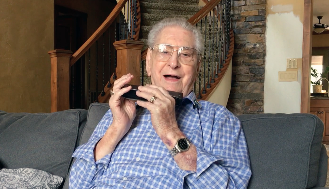 portrait of harold maurer seated on a couch holding his harmonica