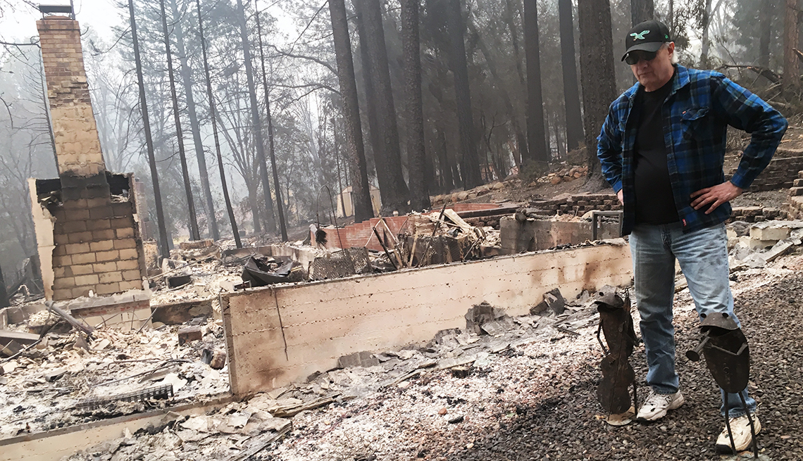 man standing next ot the ruins of his home that was destroyed in the paradise camp fire