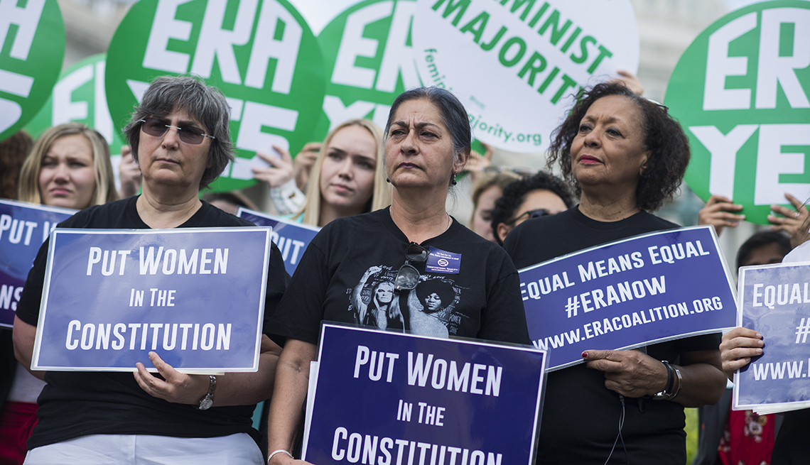 Women hold signs saying E R A Yes and Put Women in the Constitution