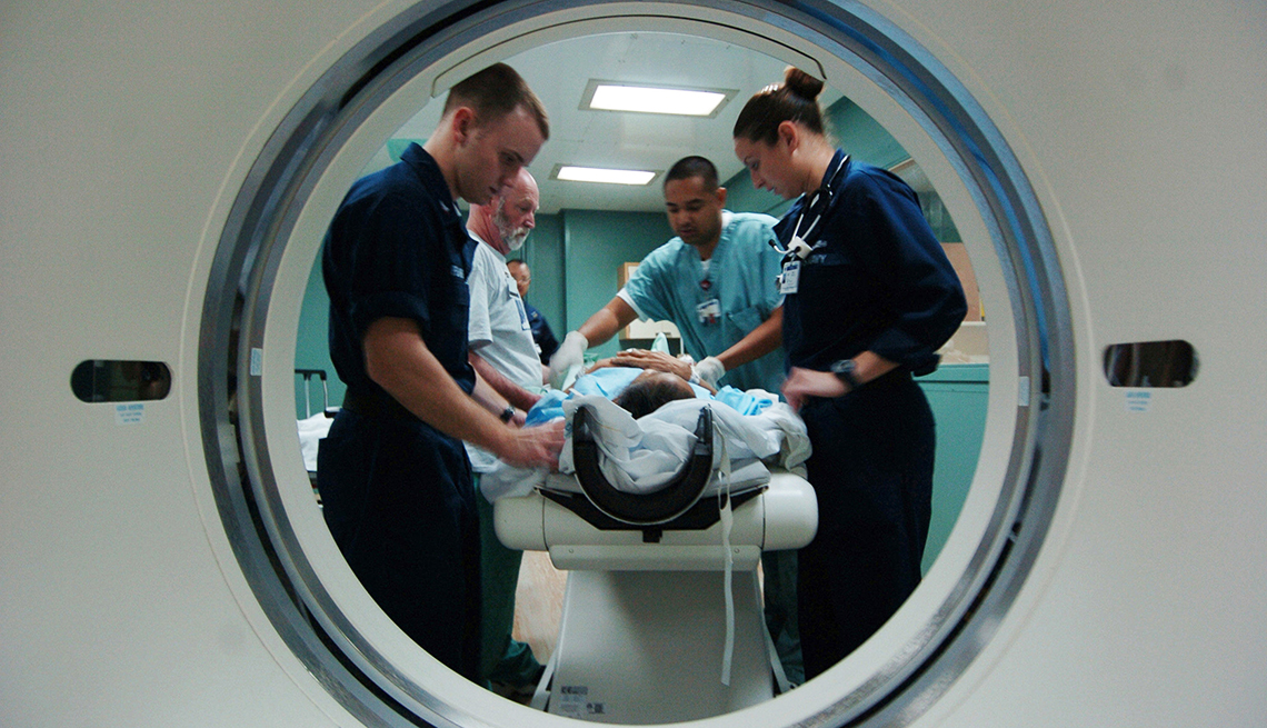 item 6 of Gallery image - four medical staff prep a patient for a cat scan