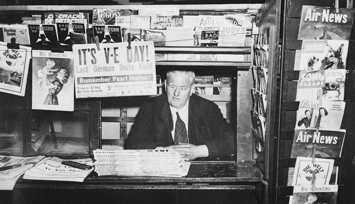 item 1 of Gallery image man inside a news stand selling papers announcing v e day in this photo from nineteen forty five