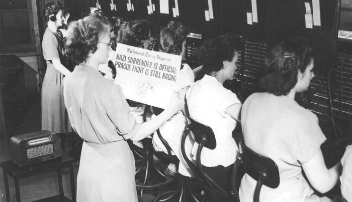 item 3 of Gallery image telephone operators working during v e day as their supervisor holds up a newspaper showing headline saying nazi surrender