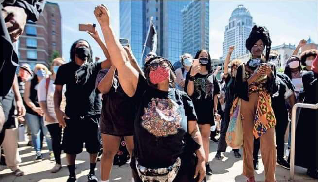 Foto de un grupo de manifestantes con Rhonda Mathies a la cabeza con el puño levantado como un gesto por la justicia racial