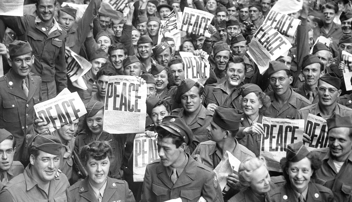 item 1 of Gallery image - Multitud de hombres y mujeres uniformados sosteniendo periódicos con un gran titular de paz