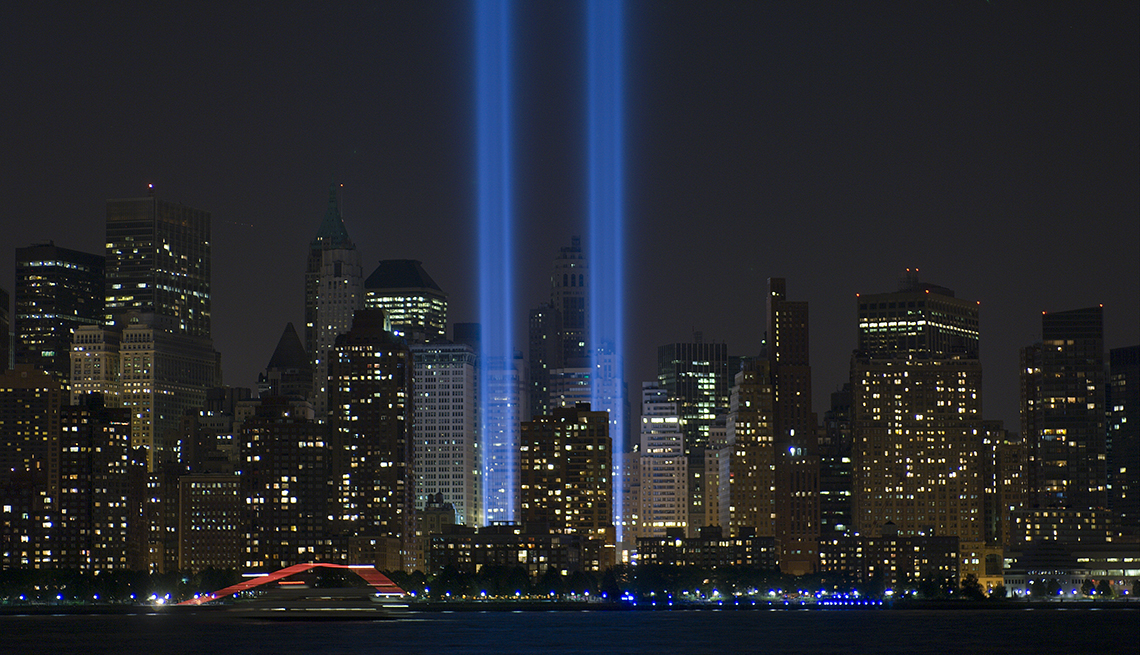 night time image of the new york city september eleventh memorial shows two towers of blue light shining from the ground at the site of the twin towers