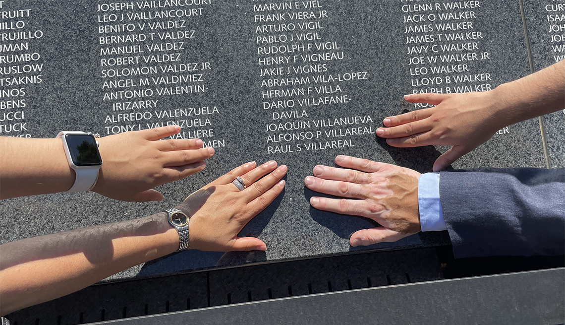 item 6 of Gallery image - hands of family and friends touching the korean war veterans memorial wall of remembrance where a name is listed