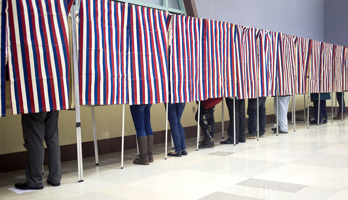 people voting in polling place with American flag stiped curtains