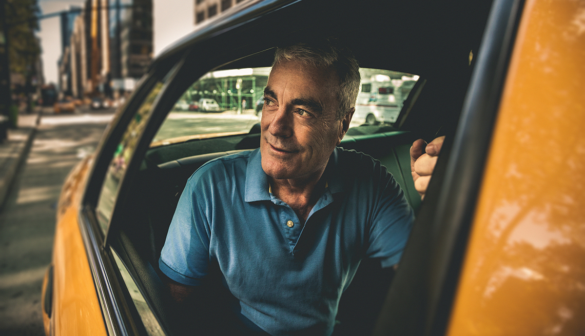Hombre mayor va en un taxi.