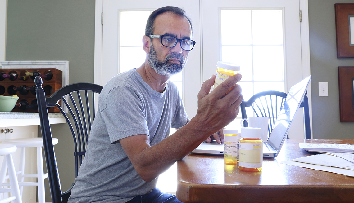 Man looking at a bottle of pills at a table