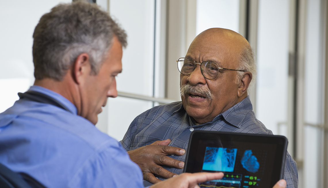 Un hombre mayor se agarra el pecho mientras habla con su médico